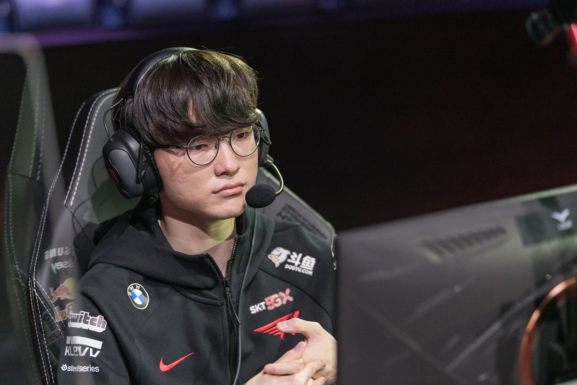 Faker sentado em uma cadeira e de frente para o computador